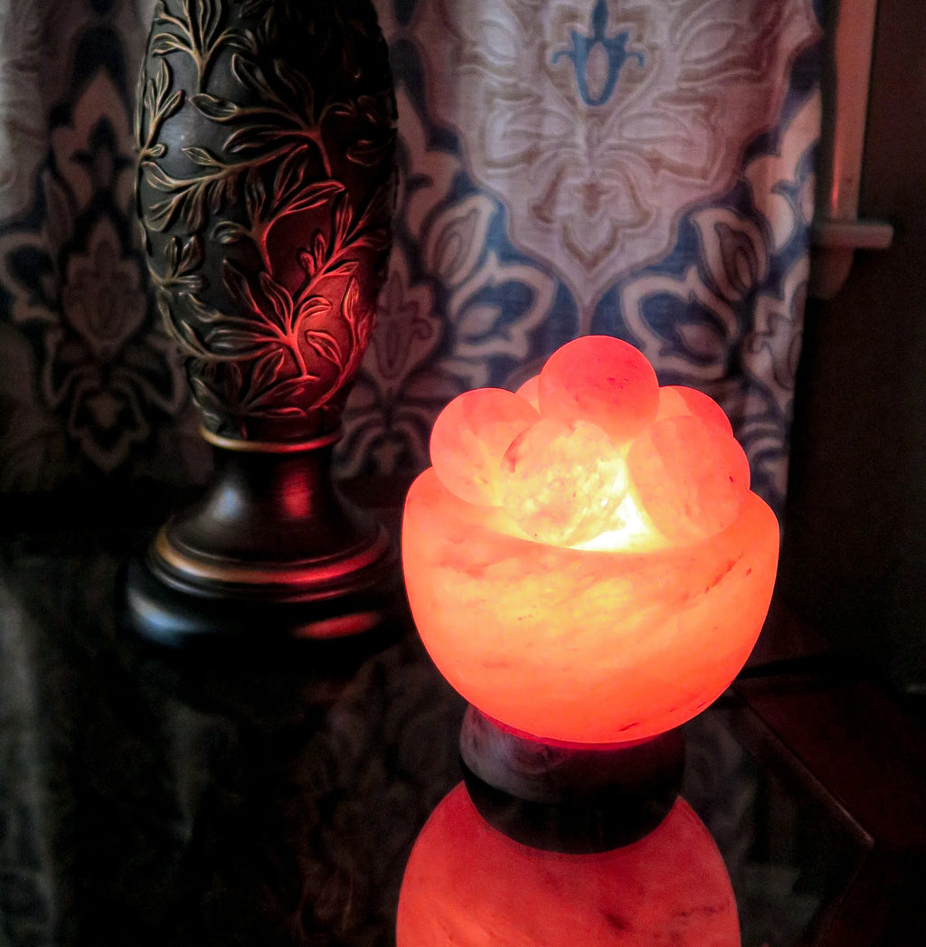 Salt bowl warmer on a reflective surface, with a patterned curtain in the background.