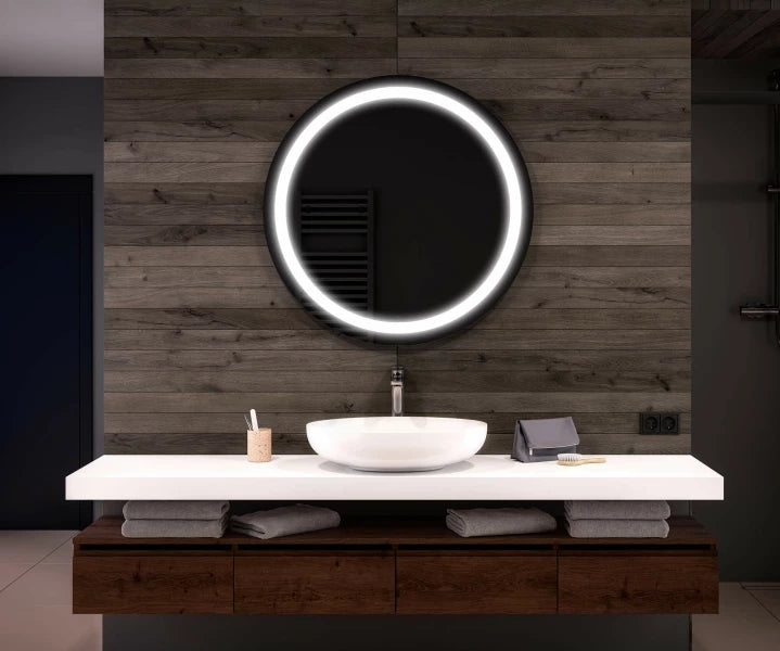 Bathroom vanity with a round illuminated mirror on a wooden wall.