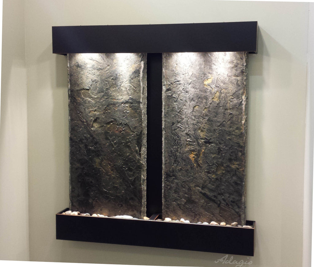 Two panel stone fountain illuminated on a wall