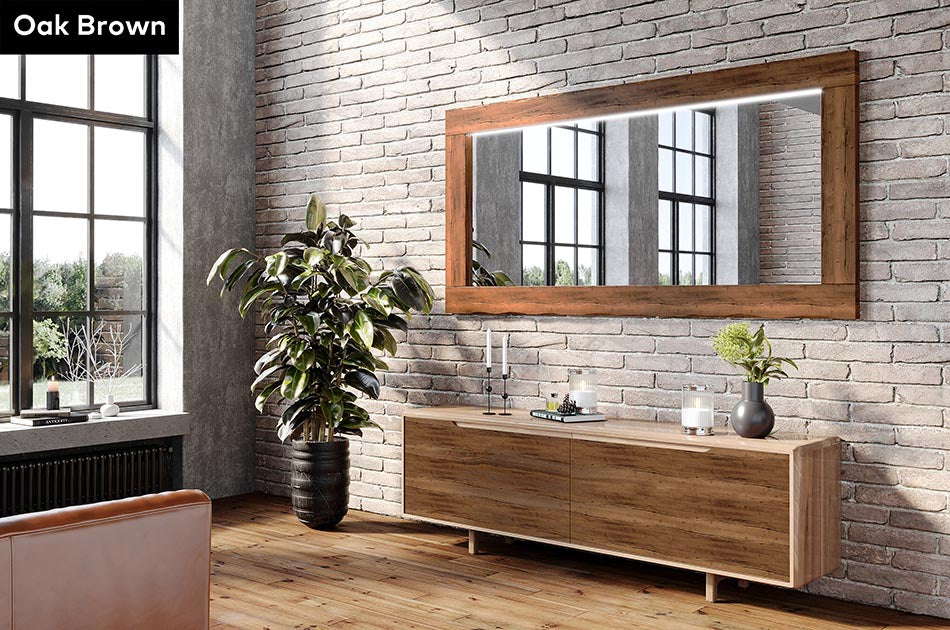Wooden dresser with Oak Brown wood-framed mirror against a brick wall in a room with large windows.