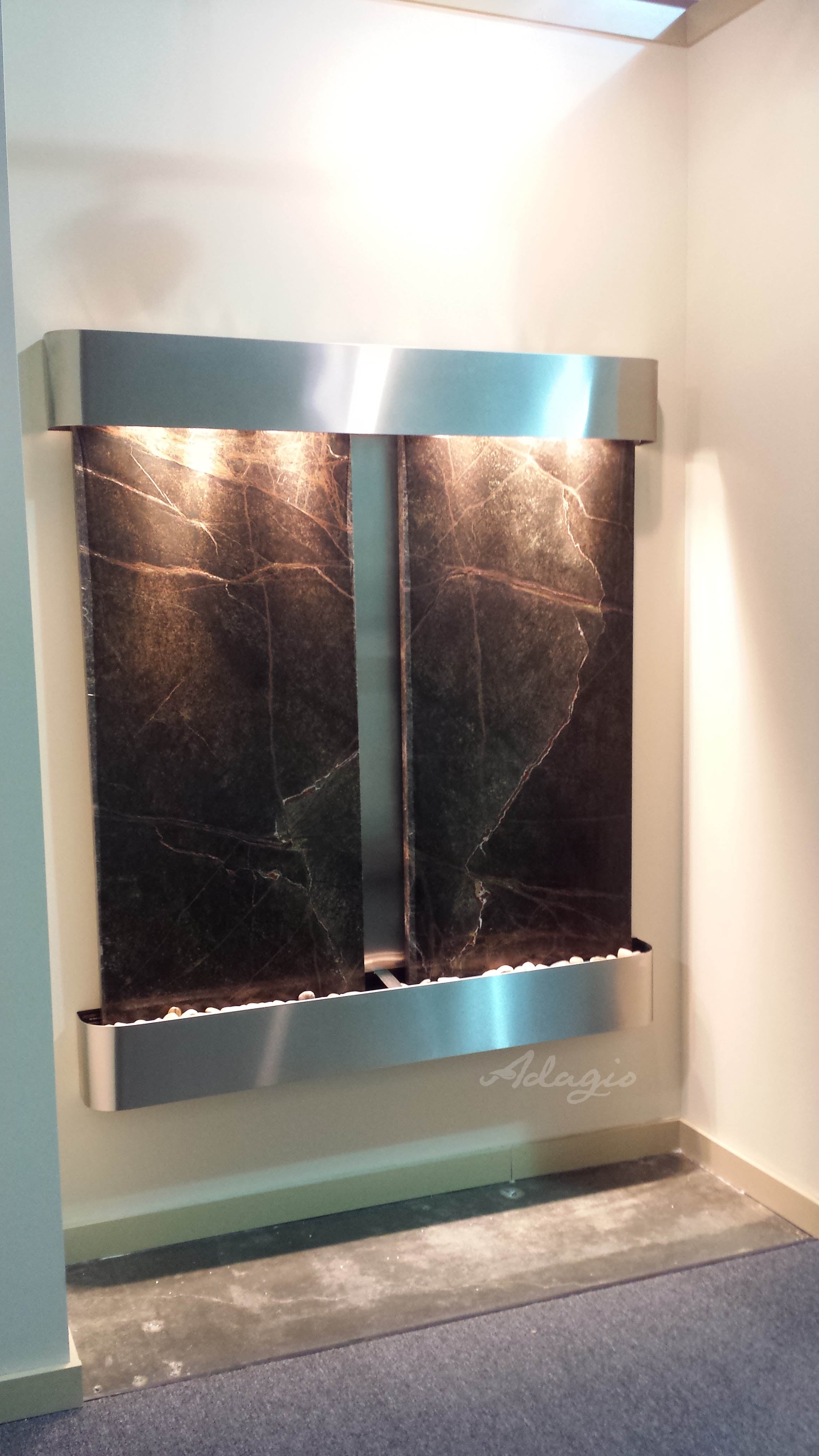 Modern wall-mounted water feature with dark marble finish and silver frame.