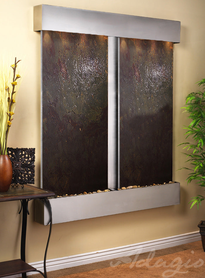 Wall-mounted water feature with dark stone panels and metallic frame on a beige wall.