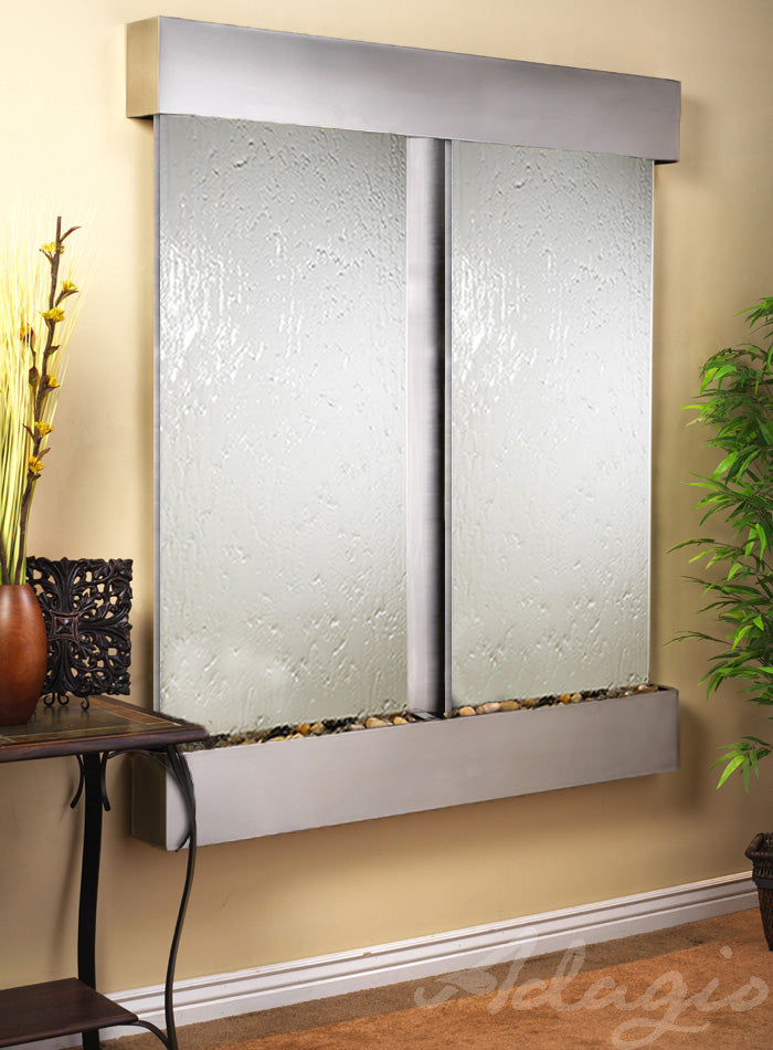 Wall-mounted water feature with reflective surface and decorative elements on a beige wall.