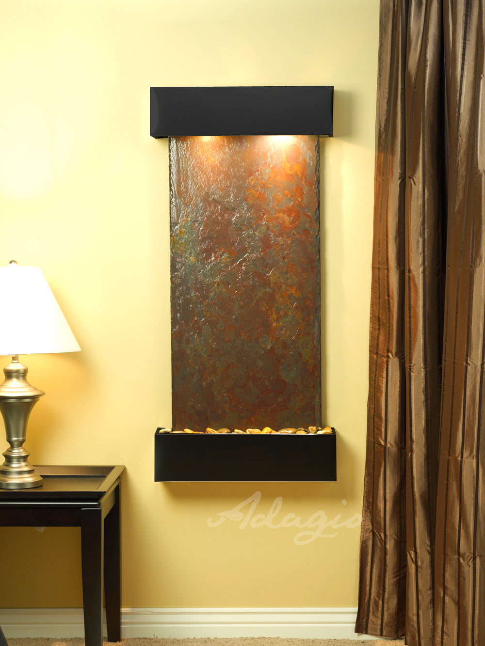Decorative wall fountain with multicolor slate panel and black frame on a yellow wall.