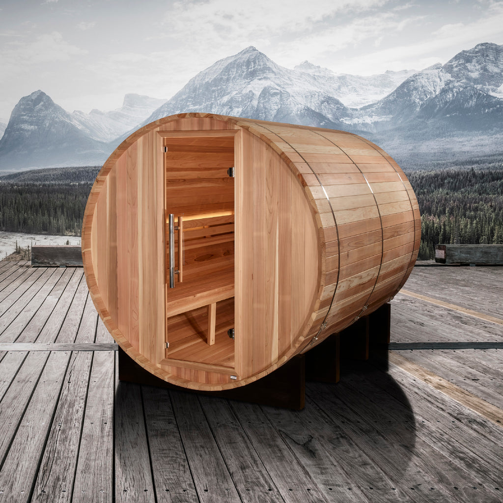Wooden barrel-shaped sauna on a wooden deck with mountains in the background