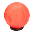 Spherical pink salt lamp with wooden base on a white background