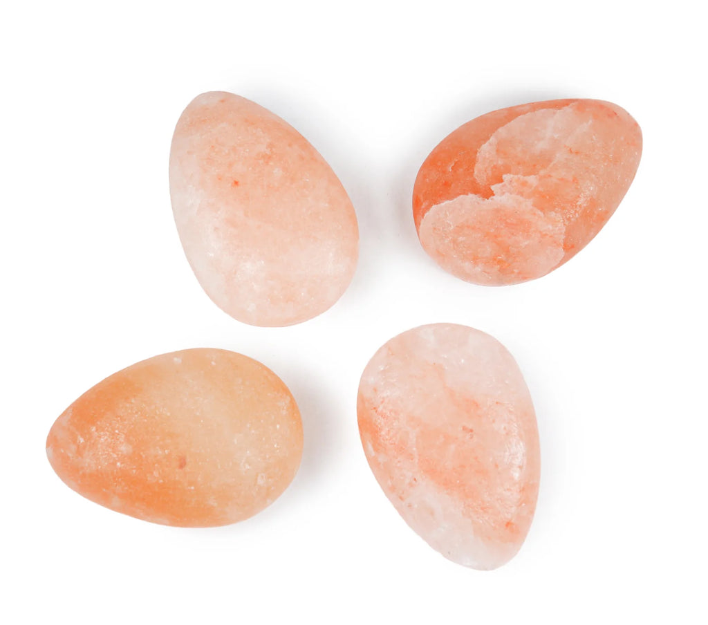 Four pink Himalayan salt rocks on a white background