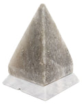 Pyramid-shaped salt lamp on a white base with a white background