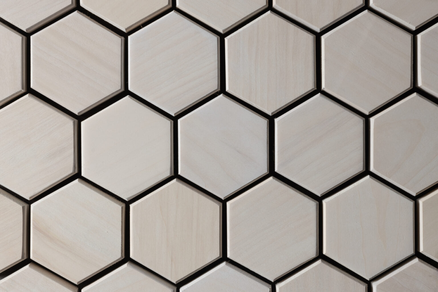Hexagonal tiles with a neutral color palette on a tiled wall.