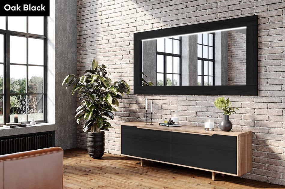 Modern interior with a wooden console table, Oak Black wood-framed mirror, and plants against a brick wall.