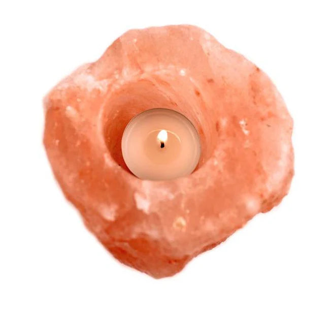 Candle inside a pink Himalayan salt lamp on a white background